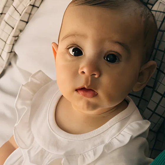 Un bébé au visage masqué par un smiley.