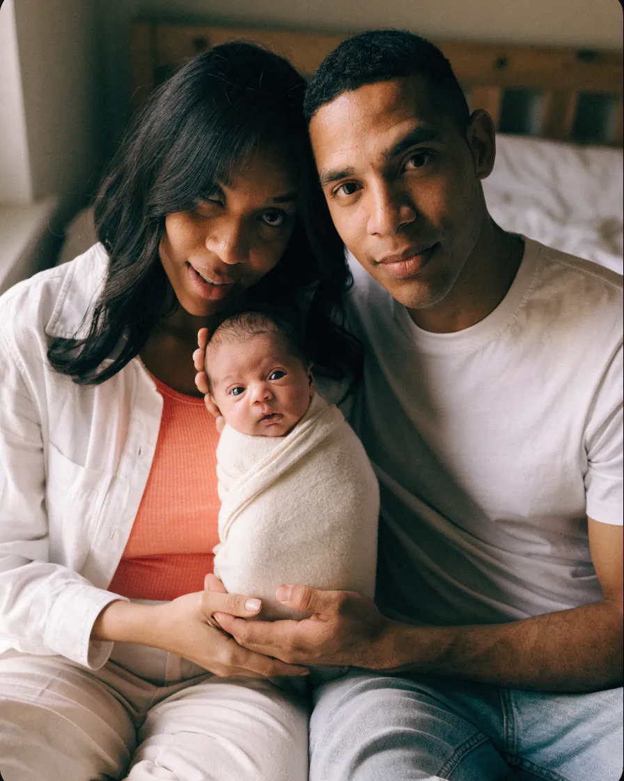 Des parents tiennent leur nouveau-né, dont le visage est masqué par une étoile.